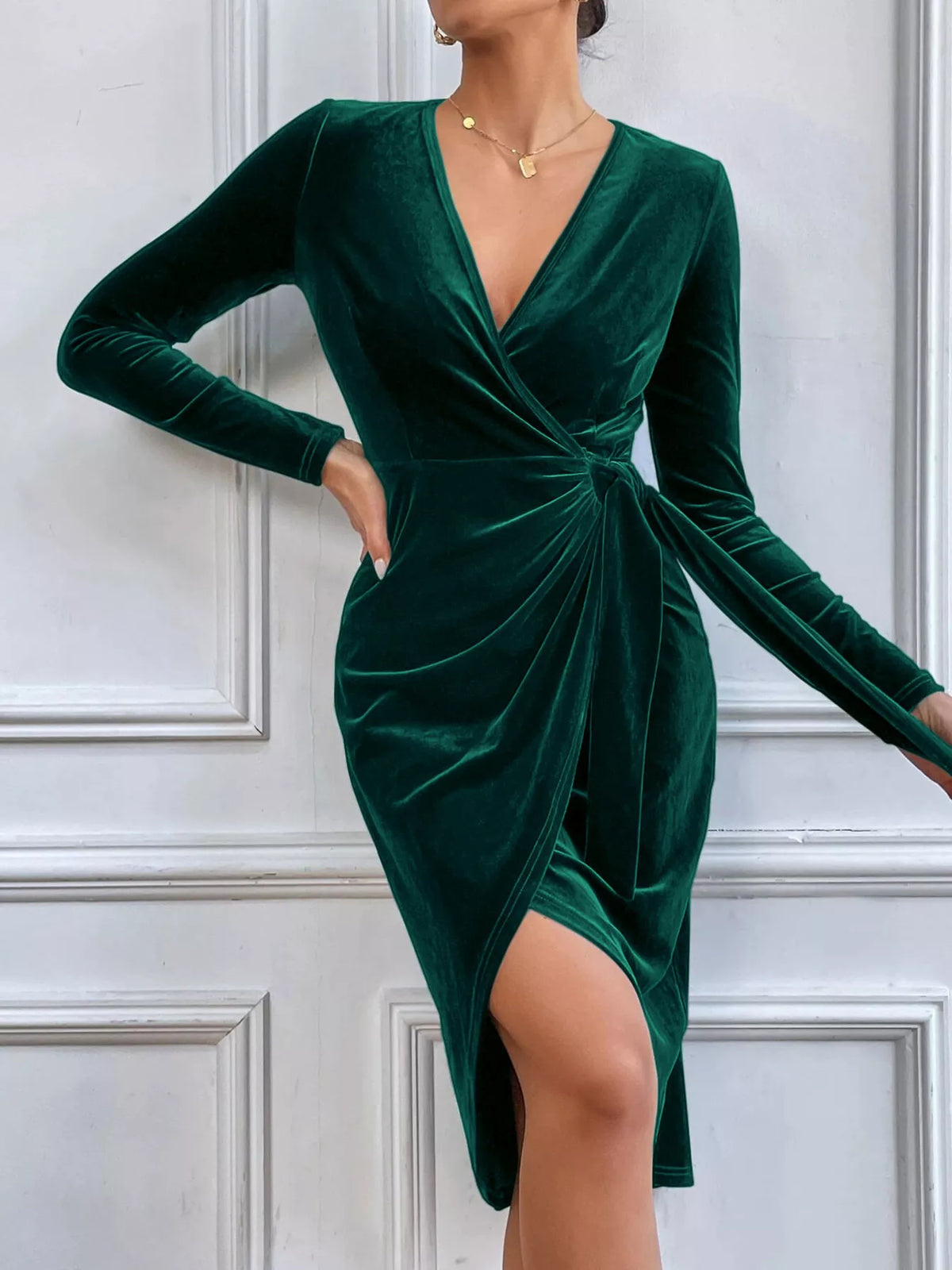 Dark green velvet midi dress with long sleeves, a crossover neckline, twisted waist and slit.